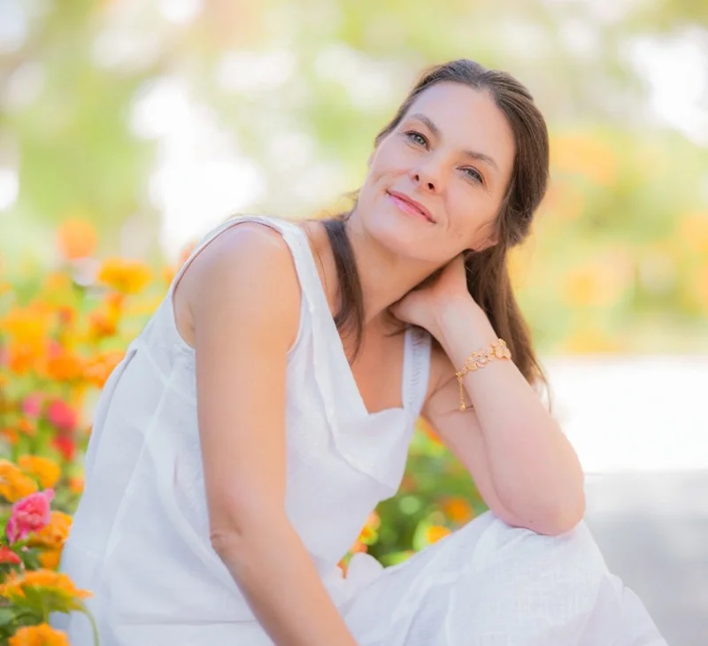 Laure B. masseuse à Marseille en blanc assise dans un jardin
